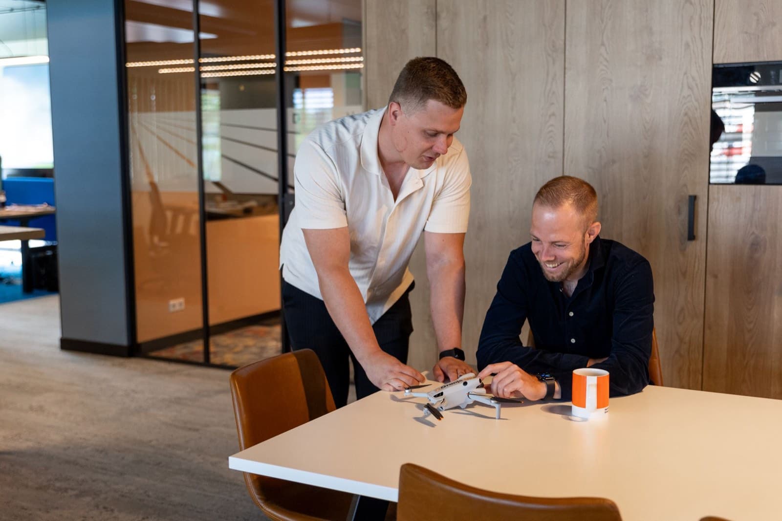Twee collega's van Oranje Uil bekijken samen een drone aan de vergadertafel
